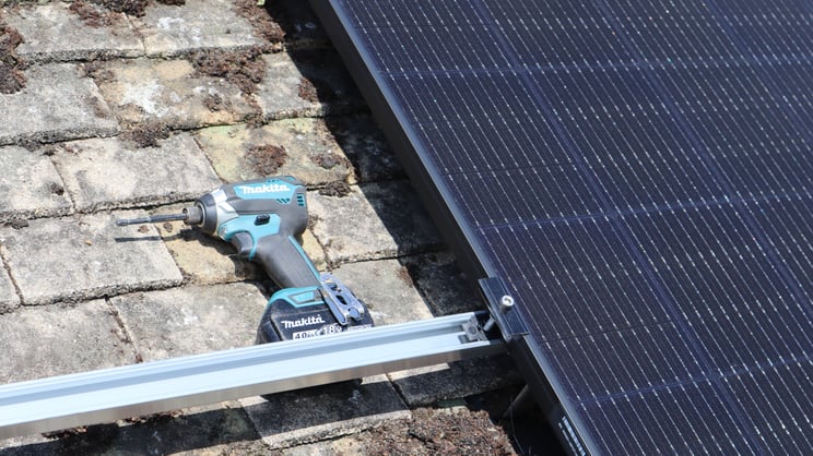 Drill next to black solar panel on railing